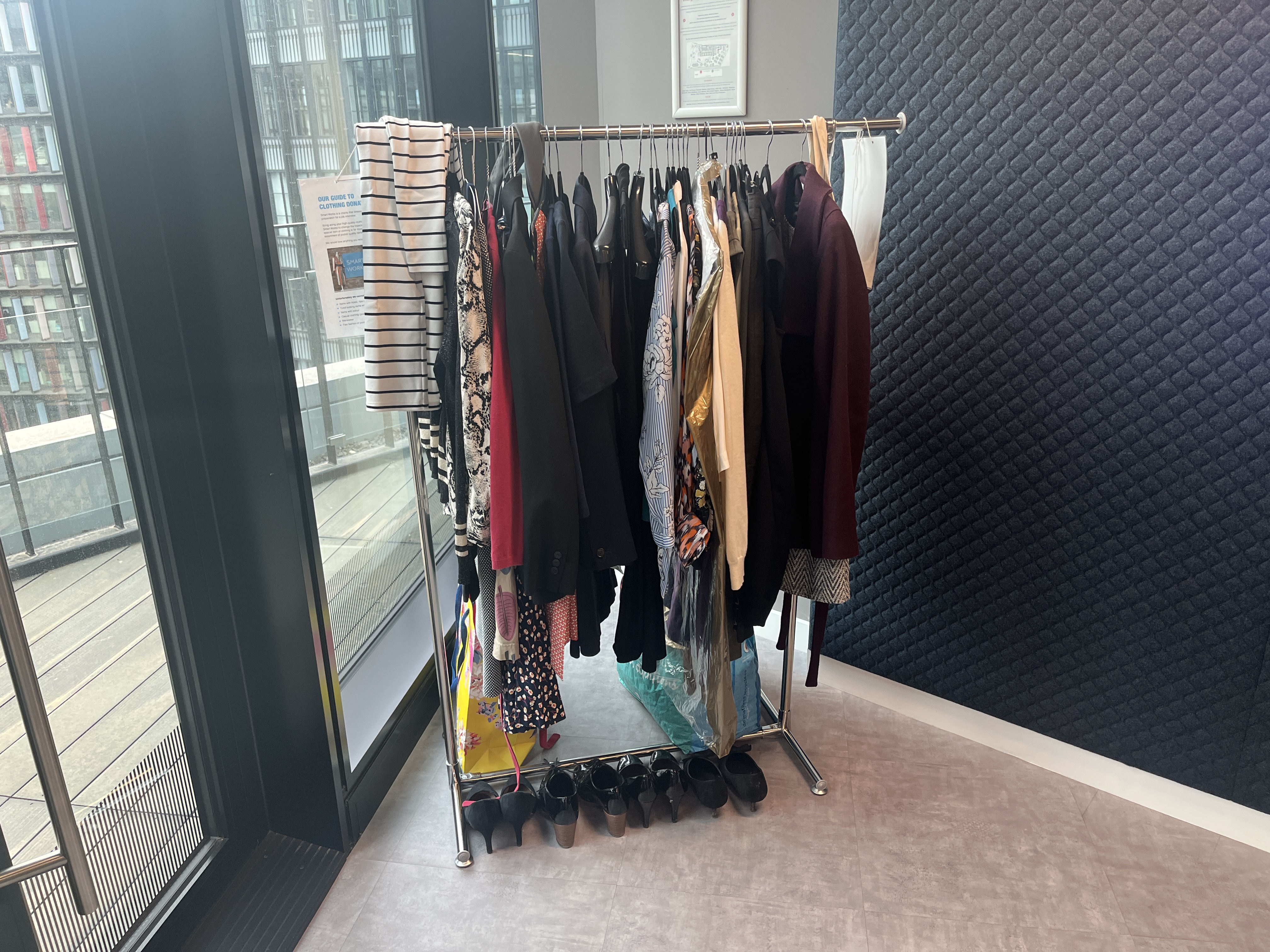 Clothing rack, filled with womenswear, with a row of shoes below
